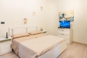 a white bedroom with a bed and a flat screen tv at Zen Retreat with Jacuzzi, Patio & Private Garage Plus Automatic Check in 24 7 with Netflix Dazn and Disney Plus in Casale Monferrato