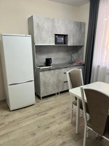 a kitchen with a white refrigerator and a table at Guest house Stella in Cholpon-Ata