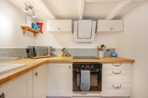 a kitchen with white cabinets and a stove top oven at Artist Cottage - Kirkudbright in Kirkcudbright +11 photos