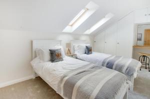 two beds in a room with white walls at Swallows Roost in Sudbury