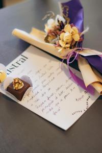 a note with a piece of chocolate and flowers on it at Pousada Austral Suítes in Imbituba