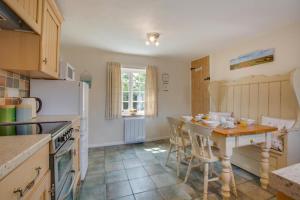 eine Küche mit einem Tisch und einem weißen Kühlschrank in der Unterkunft Town Yard Cottage in Cley next the Sea + 7 Fotos
