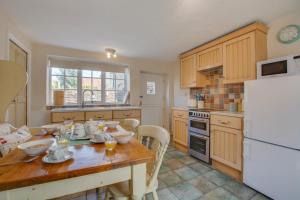 eine Küche mit einem Holztisch und einem weißen Kühlschrank in der Unterkunft Town Yard Cottage in Cley next the Sea