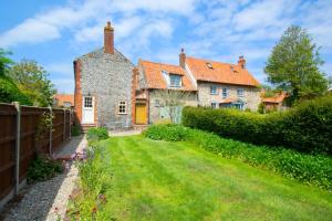 ein altes Steinhaus mit einem Zaun und einem Hof in der Unterkunft Town Yard Cottage in Cley next the Sea