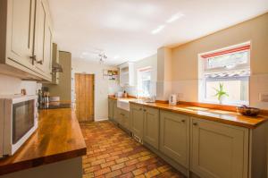 a large kitchen with wooden counter tops and a window at Barn Meadow Cottage in Yoxford
