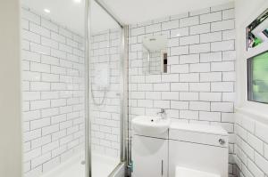 a white bathroom with a sink and a shower at Barn Meadow Cottage in Yoxford +9 photos