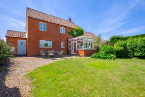 a brick house with a patio and a yard at Church Meadow Cottage in Trimingham