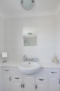 a white bathroom with a sink and a mirror at Church Meadow Cottage in Trimingham +16 photos