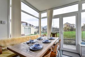 ein Esszimmer mit einem Tisch und großen Fenstern in der Unterkunft Sandy Dell in Beadnell