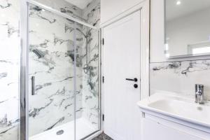 ein weißes Badezimmer mit Dusche und Waschbecken in der Unterkunft Sandy Dell in Beadnell + 16 Fotos