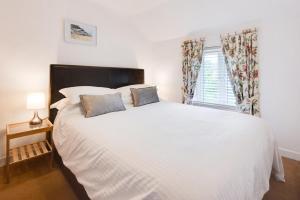 a bedroom with a large white bed with two pillows at Poppy Cottage in Briston