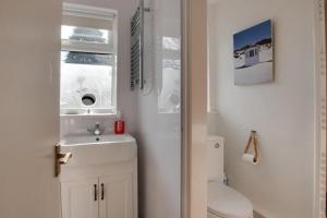 a bathroom with a sink and a toilet and a window at Poppy Cottage in Briston +11 photos
