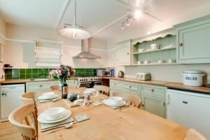 eine Küche mit einem Holztisch mit Stühlen und einem Esszimmer in der Unterkunft Coldburn Cottage in Kirknewton