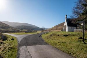 eine Straße, die zu einer kleinen weißen Kirche auf einem Hügel führt in der Unterkunft Coldburn Cottage in Kirknewton
