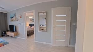 une pièce avec une chambre avec un lit et un miroir dans l'établissement GARDENIA Apartament Przy Plaży 17, à Dziwnów