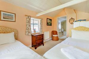 a bedroom with two beds and a window at Coach House Cottage in Wickham Market