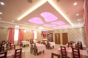 a restaurant with white tables and chairs and pink ceilings at Mirage Hotel in Berehove