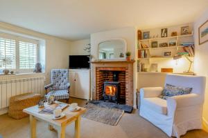 a living room with a fireplace and a chair and a table at Stone Cottages - Bodham in Bodham