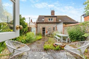 a garden with two chairs and a table and a house at Stone Cottages - Bodham in Bodham