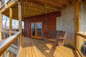 a porch with a swing in a log cabin at Climbing to New Heights cabin in Cartertown