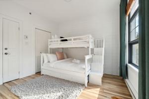 Ce lit superposé blanc se trouve dans un dortoir doté d'un tapis. dans l'établissement Les Eaux Luxe Mountain View Condo Private Sauna, à Mont-Tremblant