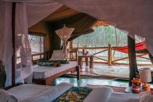 a bedroom with two beds and a porch with a deck at Angalia Tented Camp in Mikumi