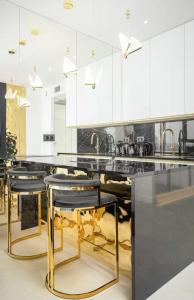 a kitchen with white cabinets and black tables and stools at Goldstar Apartament- Wanna z widokiem, 19 Piętro, Hanza Tower Szczecin in Szczecin
