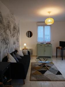a living room with a black couch and a table at La maison du verger in Magny-Fouchard