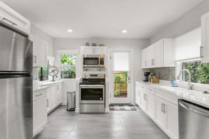 una cucina con armadietti bianchi ed elettrodomestici in acciaio inossidabile di Pool House Oasis - Home for 6 a Tampa