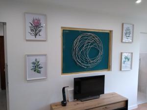 a tv on a white wall with framed pictures at Apartament Bocianek in Kielce +3 photos