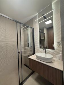 キェルツェにあるSmart Apartの洗面台とガラスのシャワーを備えたバスルーム