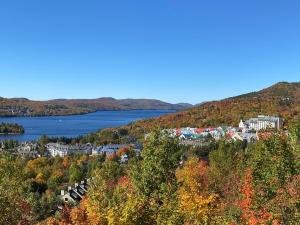 a town on a hill next to a body of water at Ski in - Ski out Condo, Hot Tub, Fireplace, Parking, Lake View in Mont-Tremblant
