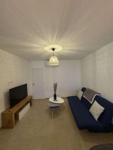 a living room with a blue couch and a tv at Appartement fraîchement rénové plein cœur du village in Saint-Fortunat-sur-Eyrieux