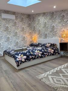 a bedroom with a large bed with a floral patterned wall at Appartement fraîchement rénové plein cœur du village in Saint-Fortunat-sur-Eyrieux