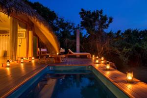 ein Haus mit einem Pool und einer Terrasse mit Beleuchtung in der Unterkunft Uga Chena Huts – All Inclusive in Yala