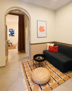 a living room with a black couch and a table at Charming 1BR in Nachlaot Steps to the Shuk in Jerusalem