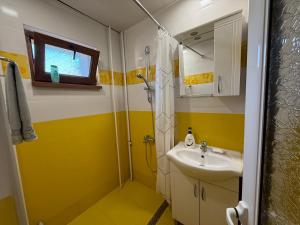 a yellow and white bathroom with a sink and shower at Central apartments Pleven in Pleven +28 photos