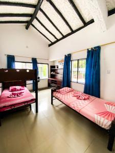 two beds in a room with blue curtains at La Juanita in Melgar +36 photos