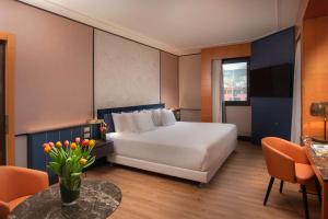 a bedroom with a large white bed and a table at NH Collection Genova Marina in Genoa
