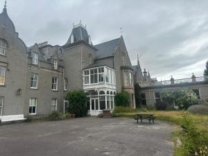 a large building with a picnic table in front of it at Cluny Hill Hotel in Forres +1 photo