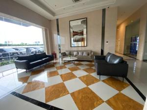 a living room with leather furniture and a checkered floor at Apartment Sky House BSD By Moza Property in Cilenggang