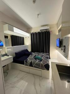 a bedroom with a bed and a desk and a television at Apartment Sky House BSD By Moza Property in Cilenggang