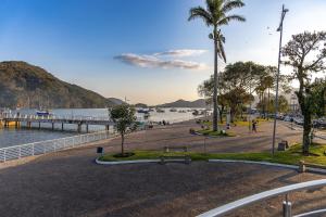 a park next to a body of water with a palm tree at 250m do Mar | Piscina e Roupas de Cama in Bertioga
