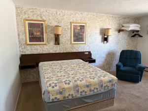 Un dormitorio con una cama y una silla azul. en Hotel O The Kings Inn Culberston MT HWY 2, 