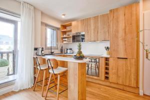 een keuken met houten kasten en een bar met krukken bij Le Morny Palace - Hyper Centre in Deauville