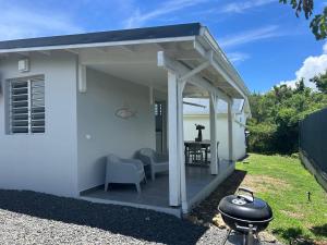 a pergola with a table and chairs on a patio at Bungalow proche de la plage de l'anse à l'eau in Saint-François