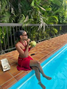 a man sitting next to a swimming pool eating food at Studio piscine & plage à Bas-du-Fort, Gosier in Le Gosier