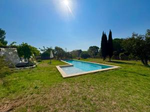 a swimming pool in the middle of a grass field at LE DOMAINE D'AMBRE La maison des Vendangeurs in Gallician