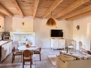 a living room with a table and a tv at LE DOMAINE D'AMBRE La maison des Vendangeurs in Gallician