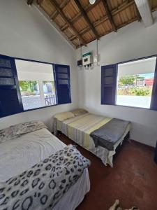 サン・フランシスコ・デ・イタバポアナにあるCasa de praia pet friendly muito aconchegante a dois minutos da praia!の窓が2つある部屋にベッドが2つある +12枚の写真